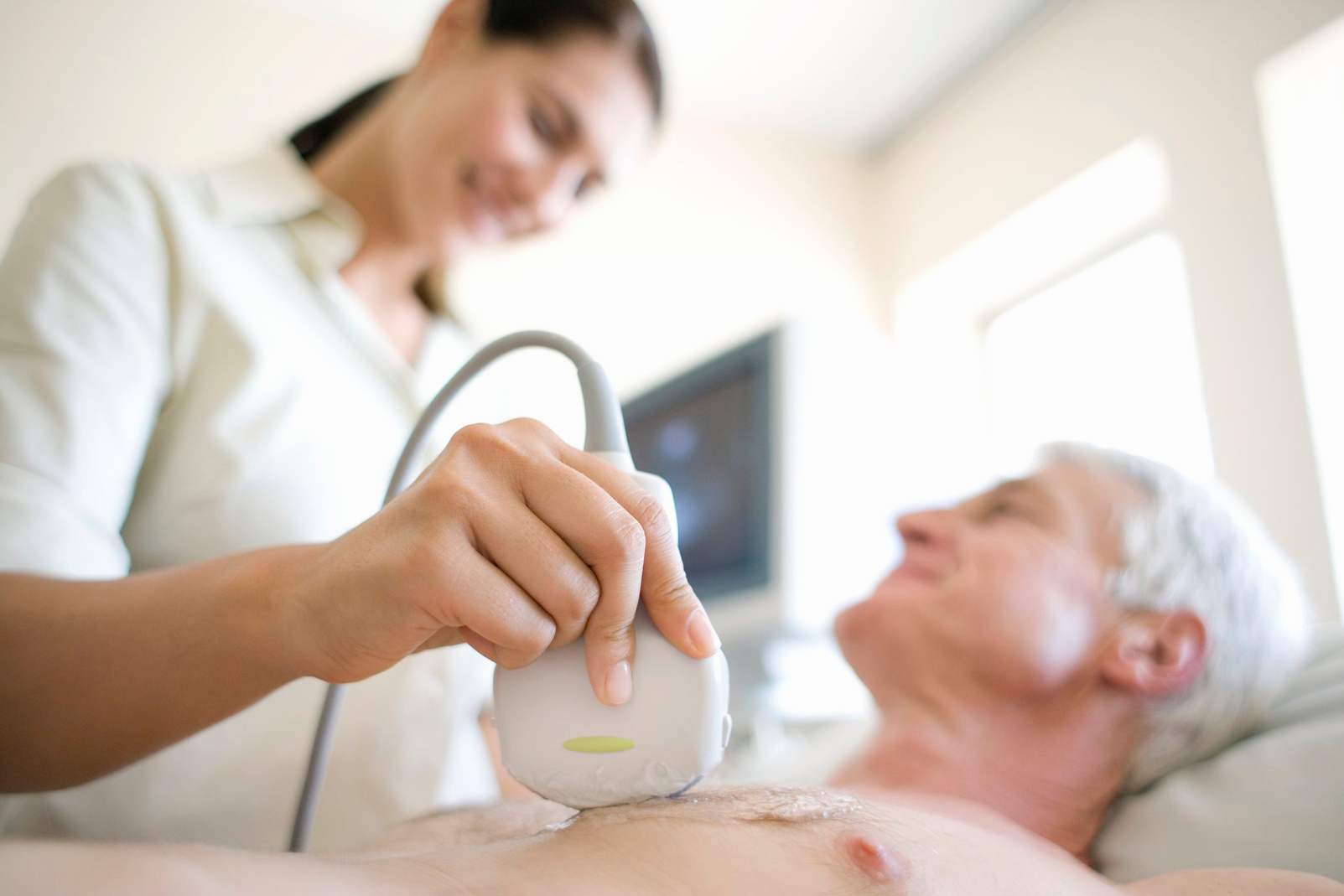 ^BMODEL RELEASED^b. ^BEchocardiography. Senior patient undergoing a heart ultrasound scan. A transducer (held against his chest) emits ultrasonic waves and detects the reflected echoes. The change in frequency is used to build images of the heart structur